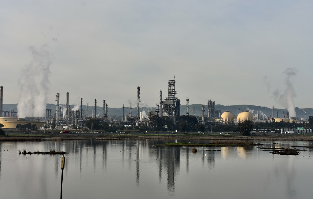 The Martinez refinery with numerous smokestacks belching effluent against the coastal hills