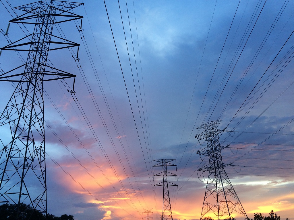 Transmission towers under gray skies with orange and yellow highlights